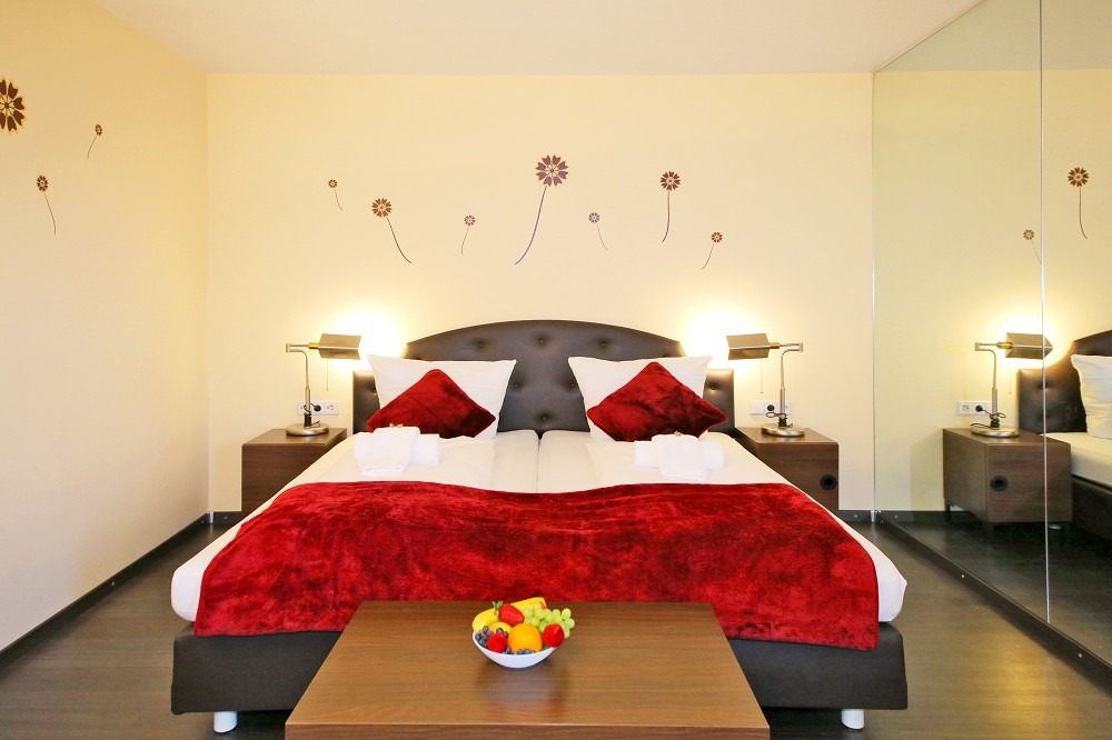 Rotes Bett, Wandblumen, Obstschale, Spiegel.